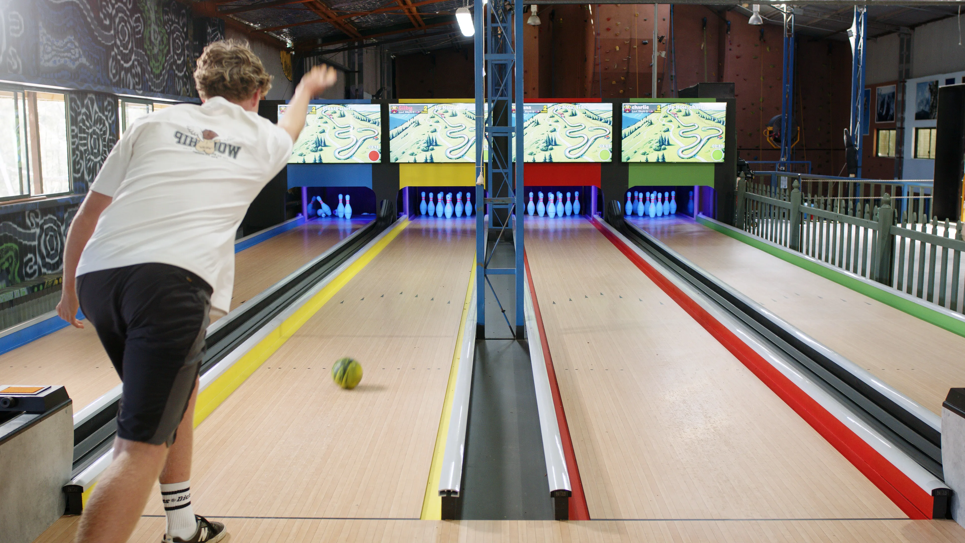 Player bowling down a LaneCraft lane with screens and UV-lit pins in the background