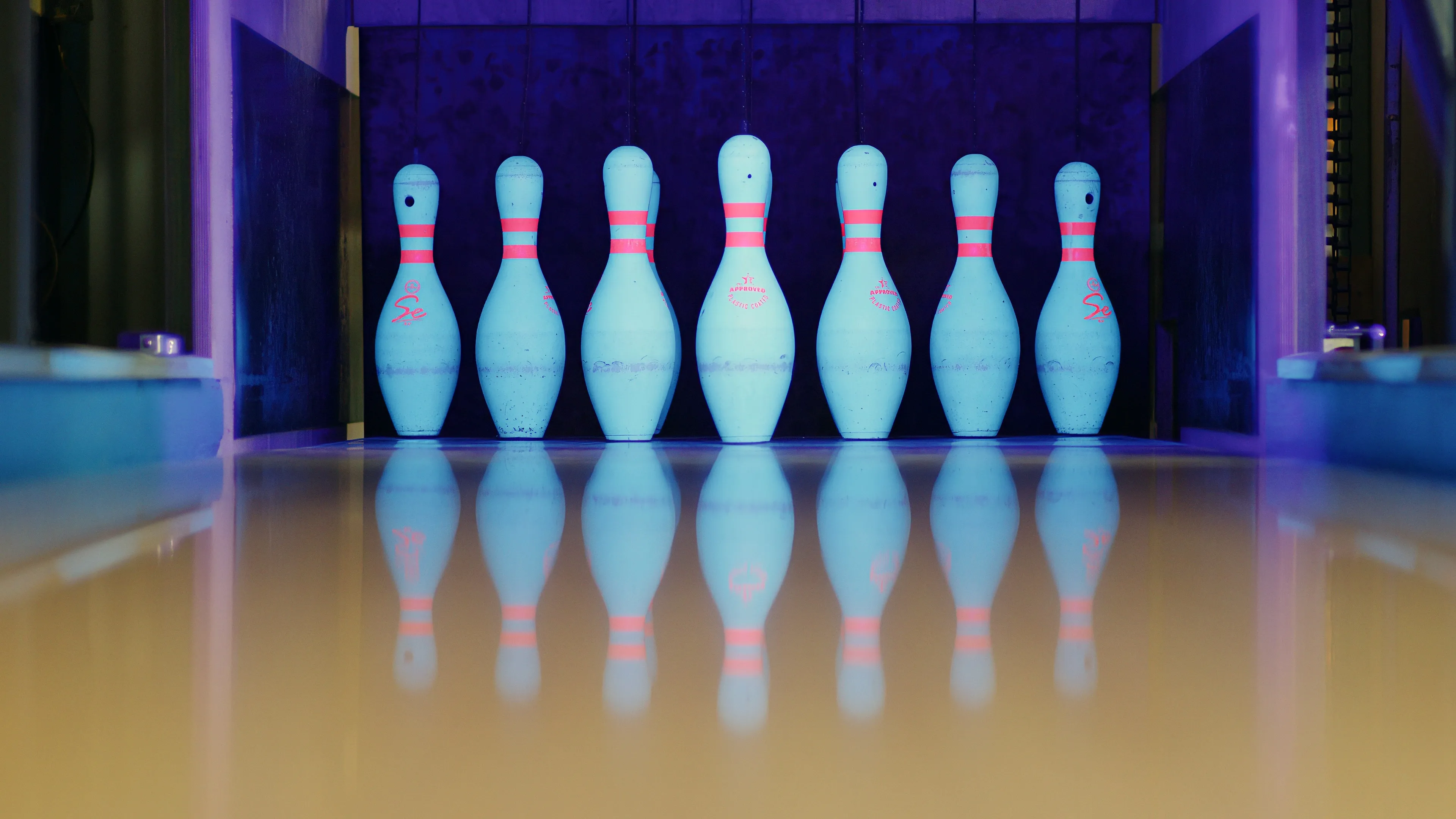 Ninepin bowling arrangement under UV lighting showing precision pin placement
