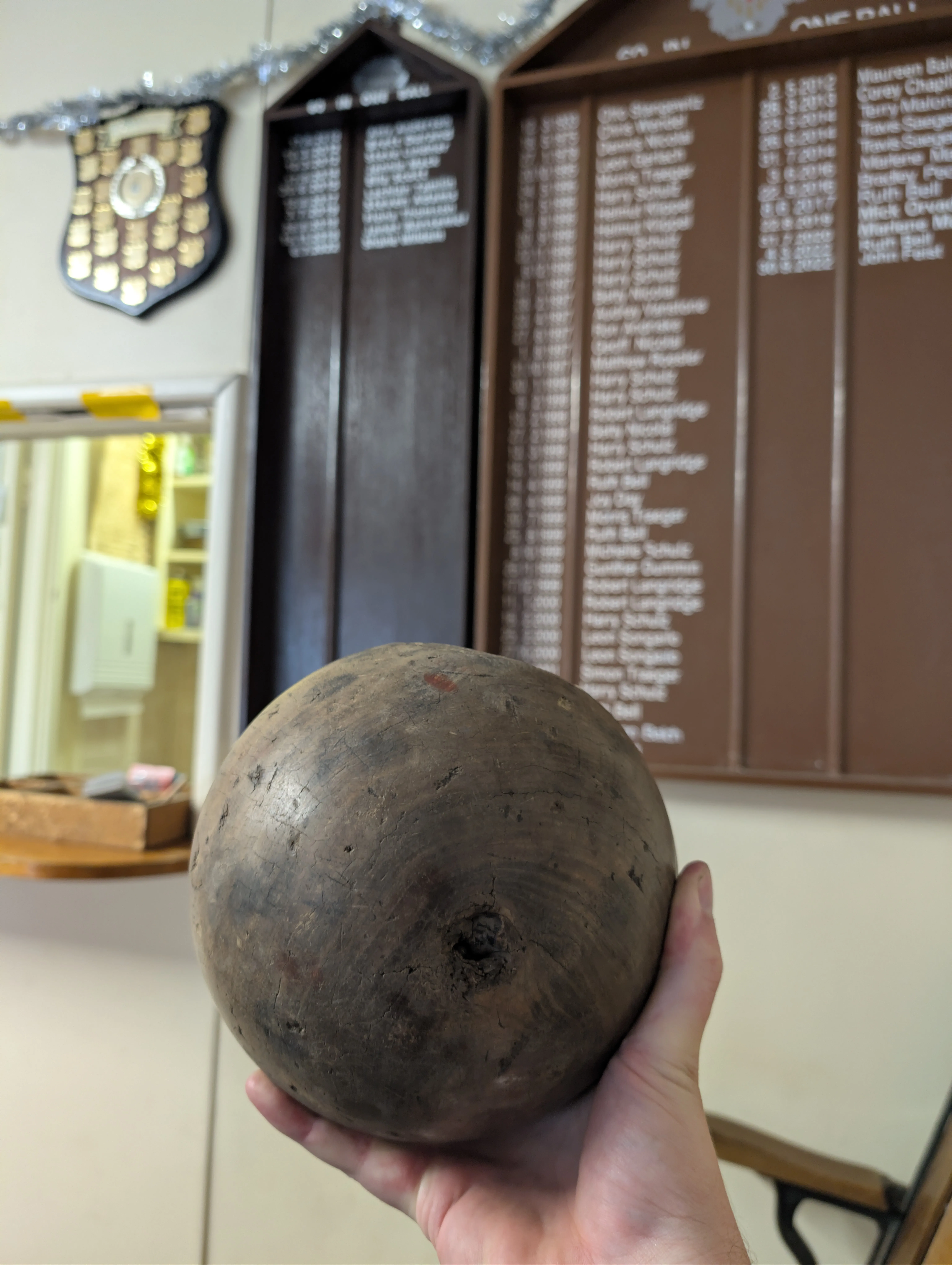 The 100-year-old wooden ball from the Tanunda Kegel Club, held against the club's honour board