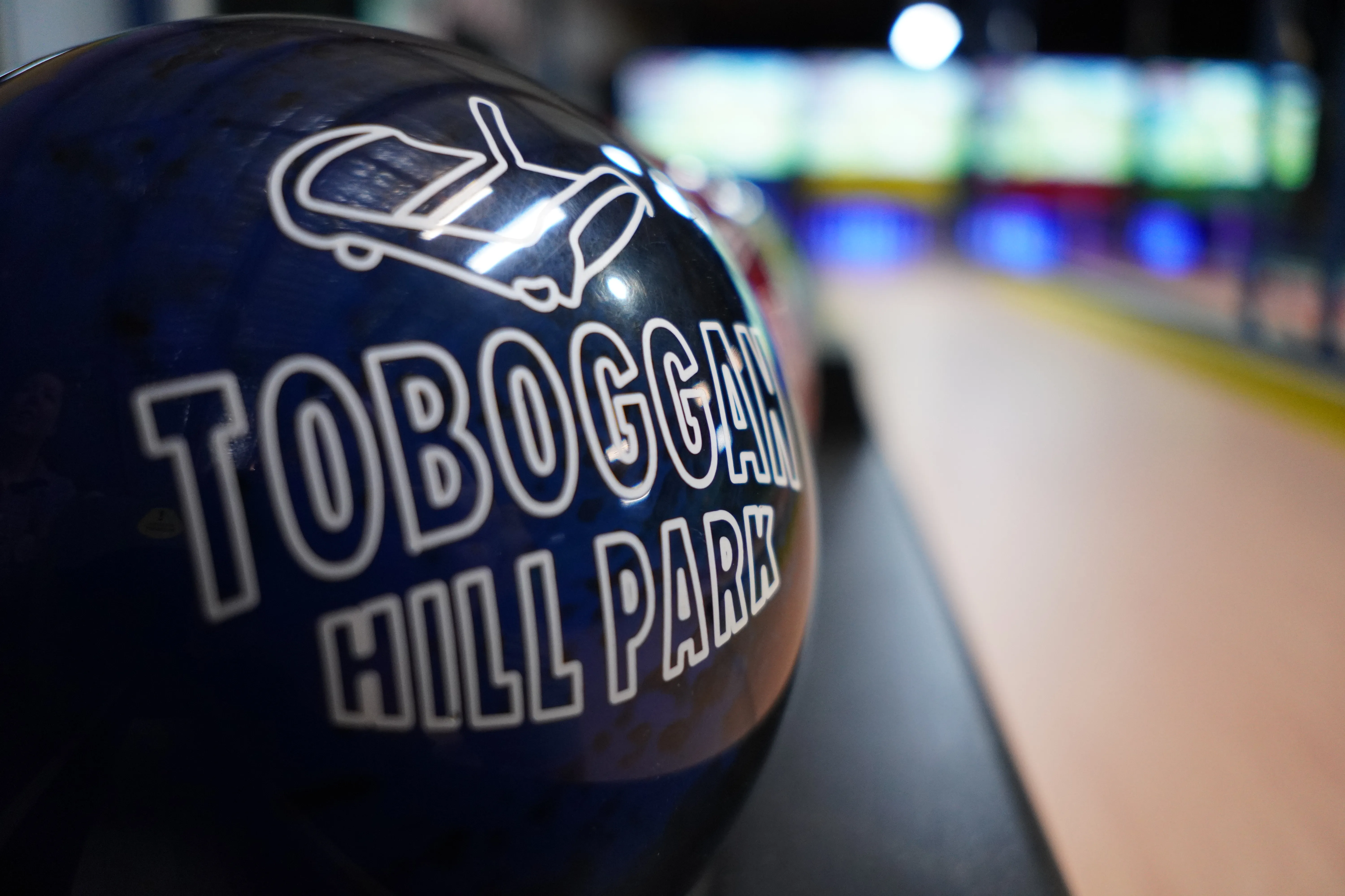 Custom branded Toboggan Hill Park bowling ball with lanes blurred in the background